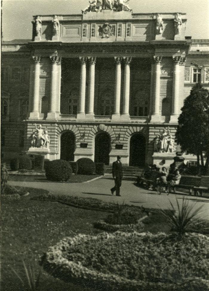 The lower terrace of Ivan Franko Park in front of Lviv University is decorated with elaborate flowerbeds and gardens. Their arrangement along the axis of the university’s main entrance has been preserved, just as it was designed in the late 19th century by the city gardener Arnold Röhring. On the right, behind the trees, one can still see a stele — one of the two that marked the entrance to the park. The decorative shrubs in the flowerbed are trimmed in layered shapes, and at its center, since 1956, there has been a commemorative marker with an inscription confirming the decision to erect a monument to the writer Ivan Franko, which was carried out in 1964.