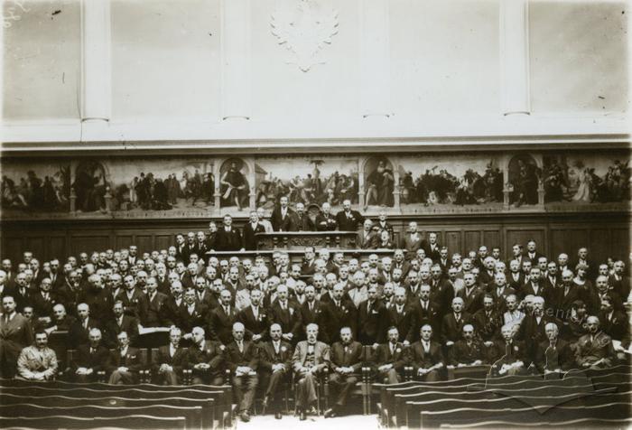 The image shows the assembly hall of Jan Kazimierz University (now Ivan Franko National University of Lviv) during an unspecified event. A large group of people is gathered in front of the camera, possibly members of the university’s faculty.